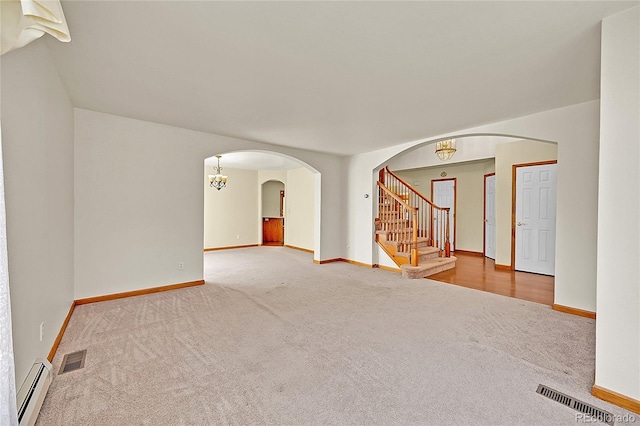 carpeted empty room featuring visible vents, a baseboard radiator, arched walkways, and baseboards