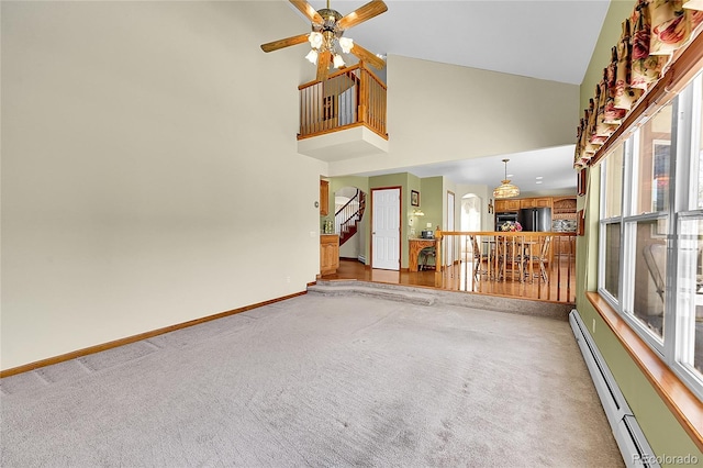 unfurnished living room featuring a baseboard heating unit, baseboards, carpet flooring, ceiling fan, and high vaulted ceiling