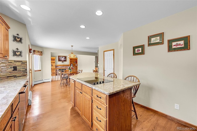 kitchen with tasteful backsplash, black electric stovetop, light wood-style floors, and a breakfast bar