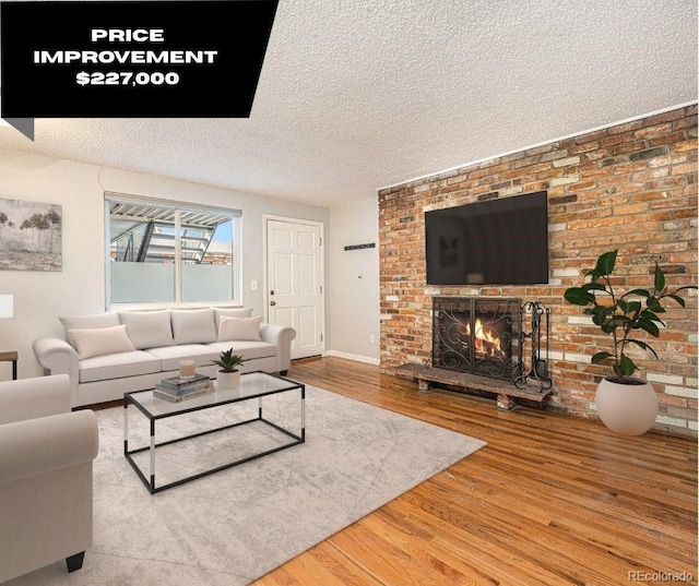 living room featuring a fireplace, a textured ceiling, and wood finished floors