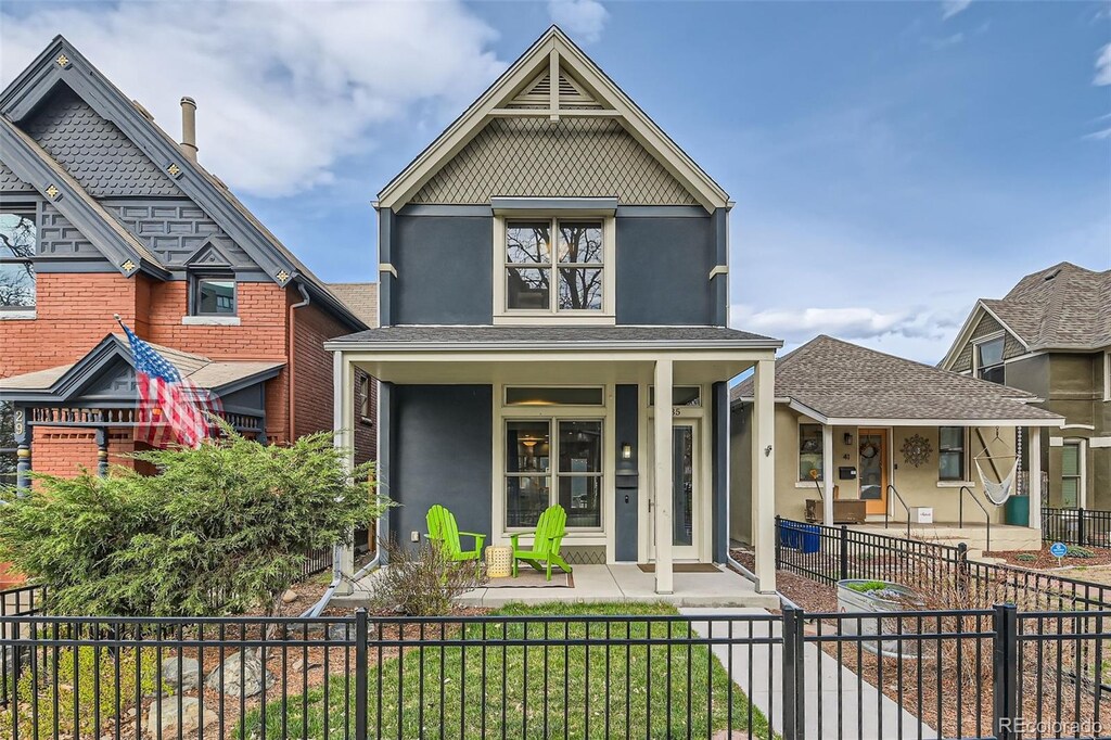 35 Elati St, Denver, CO 80223 - view of front of house with a fenced front yard, a porch, and stucco siding