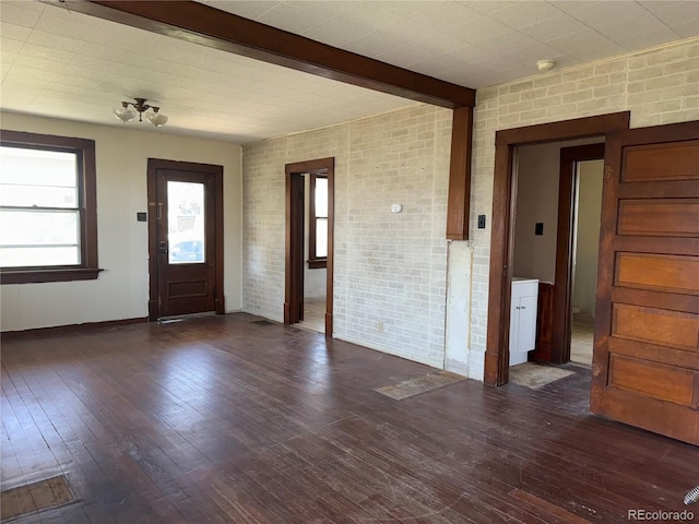 227 Milton St, Briggsdale, CO 80611 - foyer featuring brick wall, dark wood-type flooring, and beam ceiling