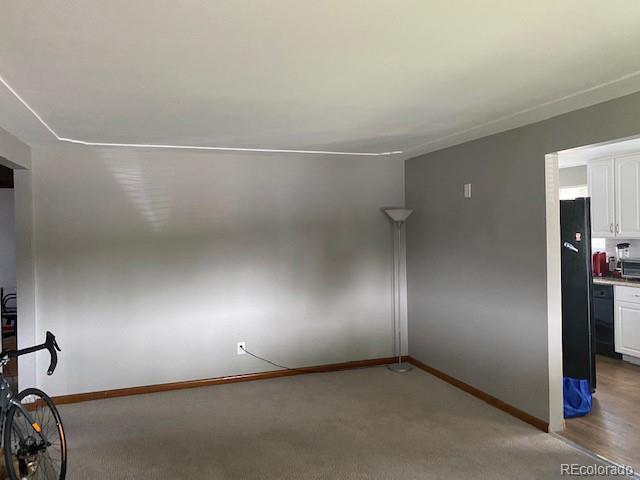 spare room with baseboards and light carpet