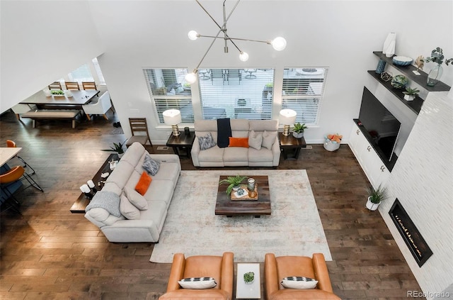 living area with an inviting chandelier, wood finished floors, and a healthy amount of sunlight