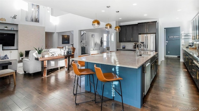 kitchen with dark wood finished floors, open floor plan, a sink, and stainless steel fridge with ice dispenser