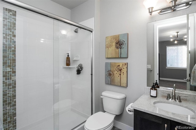 bathroom featuring a stall shower, baseboards, vanity, and toilet