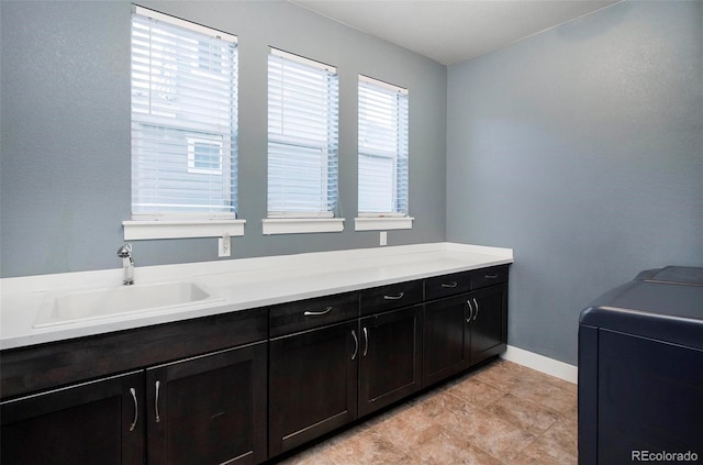 laundry area with cabinet space, baseboards, and a sink