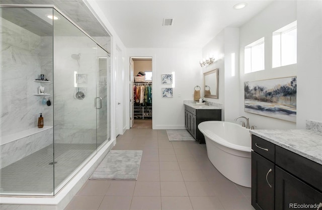 bathroom featuring a stall shower, tile patterned flooring, a walk in closet, a freestanding bath, and vanity