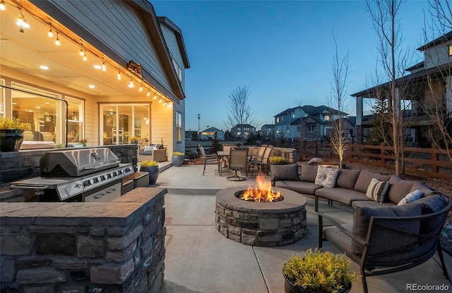 view of patio / terrace featuring an outdoor living space with a fire pit, fence, an outdoor kitchen, and area for grilling