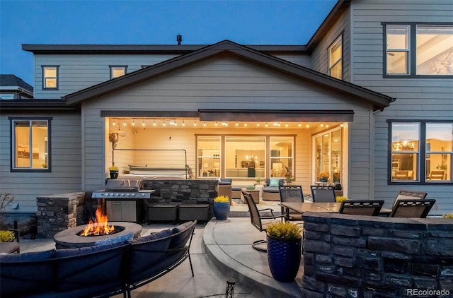 back of house with a patio area and an outdoor living space with a fire pit