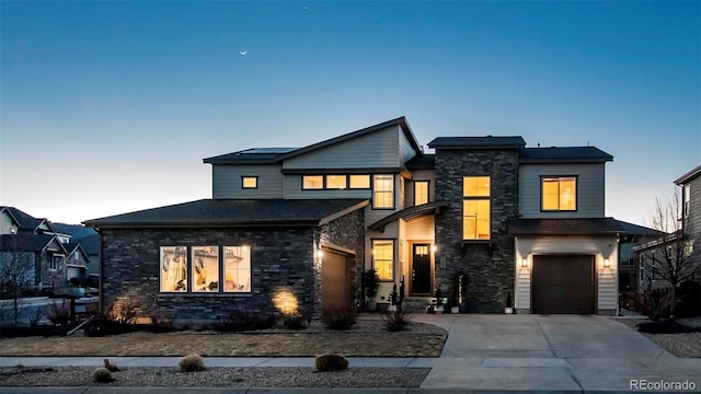 contemporary home featuring driveway, stone siding, and an attached garage