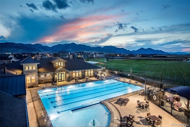 pool with a hot tub, a mountain view, fence, and a patio