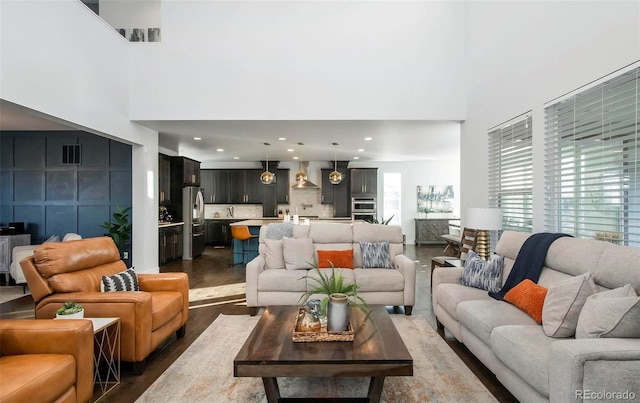 living area featuring recessed lighting, dark wood-style flooring, visible vents, and a towering ceiling