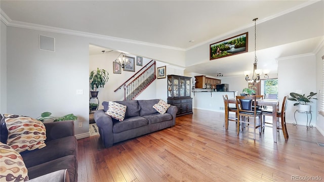 living room featuring ornamental molding, an inviting chandelier, and wood-type flooring