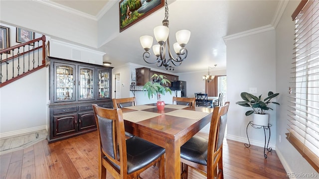 dining room with hardwood / wood-style floors, crown molding, and an inviting chandelier