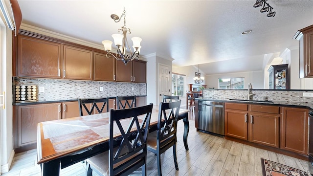 interior space featuring backsplash, sink, dishwasher, and decorative light fixtures