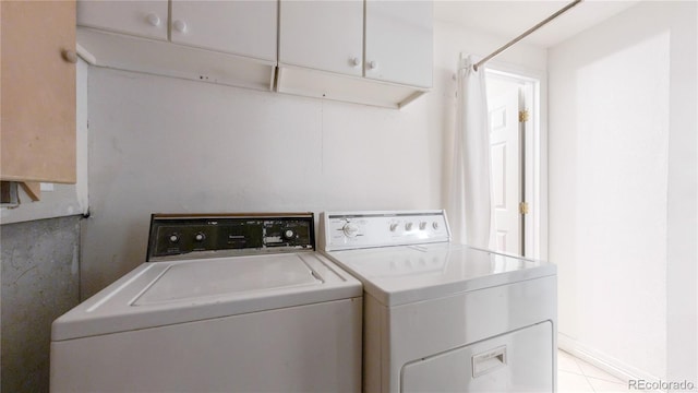 laundry area with light tile flooring, cabinets, and separate washer and dryer