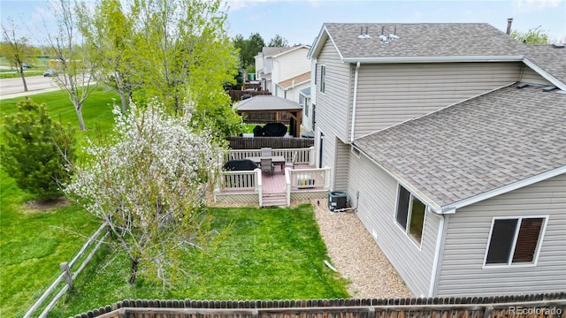 rear view of property featuring a deck, a gazebo, central air condition unit, and a lawn