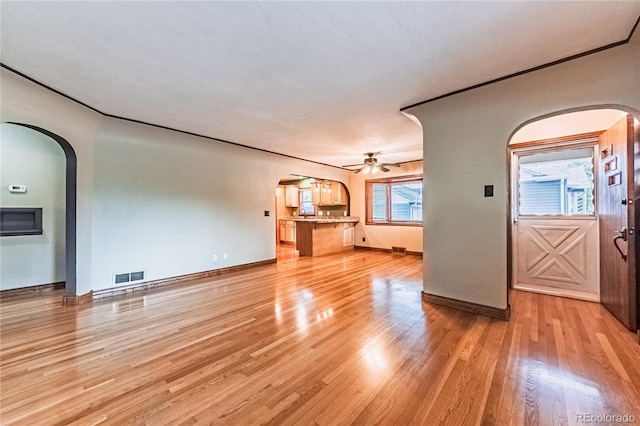 1325 N Foote Ave, Colorado Springs, CO 80909 - unfurnished living room with arched walkways, ceiling fan, light wood finished floors, and baseboards