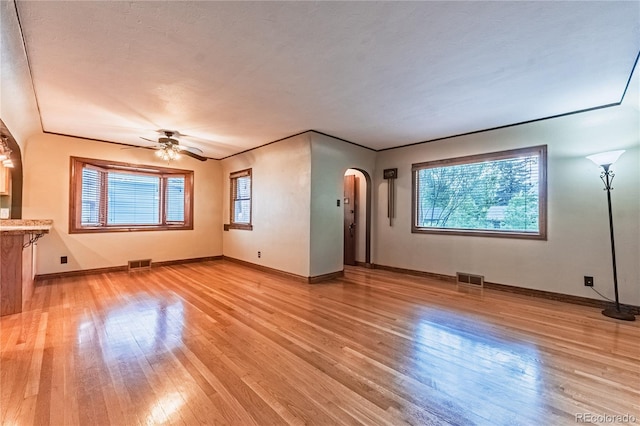 1325 N Foote Ave, Colorado Springs, CO 80909 - unfurnished living room featuring arched walkways, light wood-type flooring, healthy amount of natural light, and baseboards