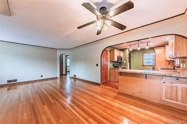 1325 N Foote Ave, Colorado Springs, CO 80909 - kitchen featuring stainless steel appliances, arched walkways, light wood finished floors, a sink, and ceiling fan