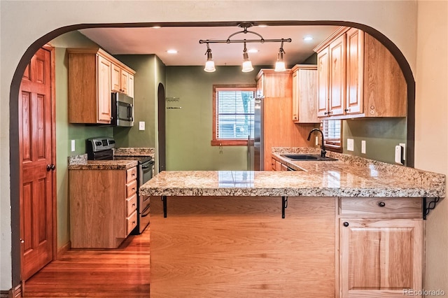 1325 N Foote Ave, Colorado Springs, CO 80909 - kitchen featuring appliances with stainless steel finishes, a sink, wood finished floors, arched walkways, and a peninsula