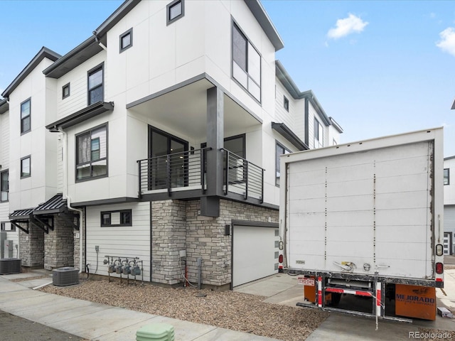 view of front of home featuring a garage, stone siding, cooling unit, and stucco siding