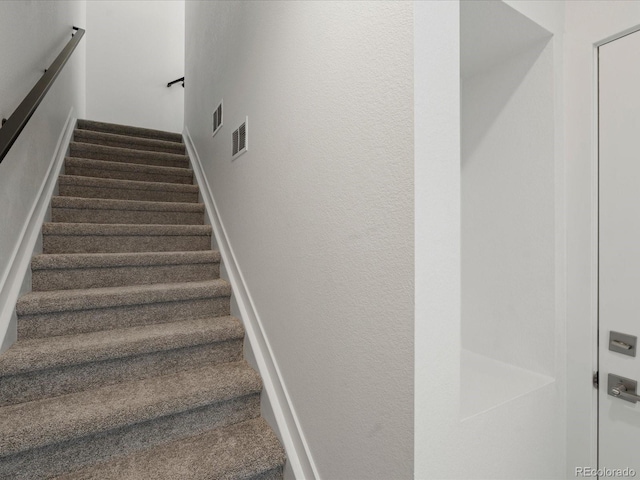 staircase featuring visible vents and a textured wall