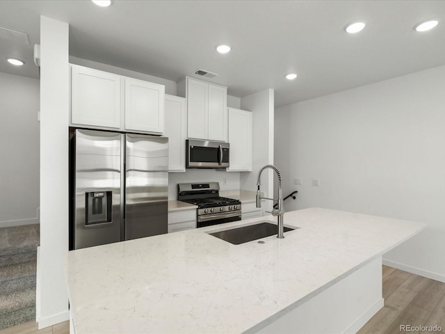 kitchen with light stone counters, a sink, visible vents, white cabinetry, and appliances with stainless steel finishes