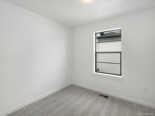 spare room with carpet, visible vents, and baseboards