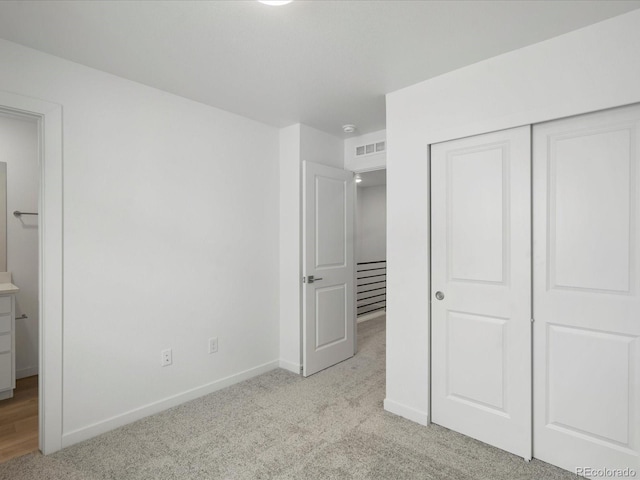 unfurnished bedroom featuring baseboards, a closet, visible vents, and light colored carpet