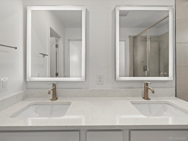 full bath with double vanity, a stall shower, and a sink