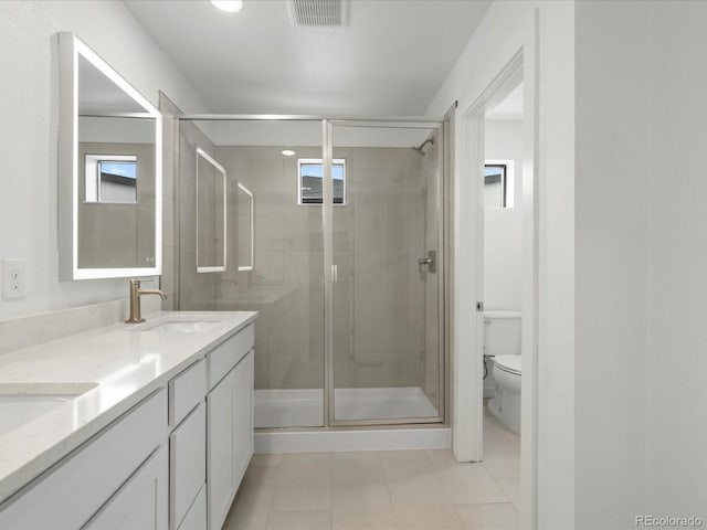 full bathroom with double vanity, a stall shower, visible vents, toilet, and a sink