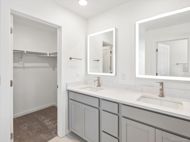 2036 S Holly St Unit 4, Denver, CO 80222 - bathroom with double vanity, a spacious closet, baseboards, and a sink