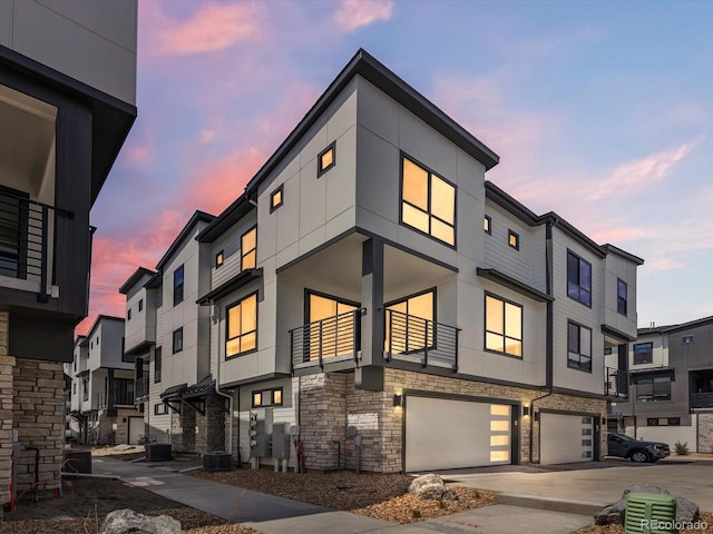 2036 S Holly St Unit 4, Denver, CO 80222 - view of front of house featuring stone siding, an attached garage, stucco siding, and central AC unit