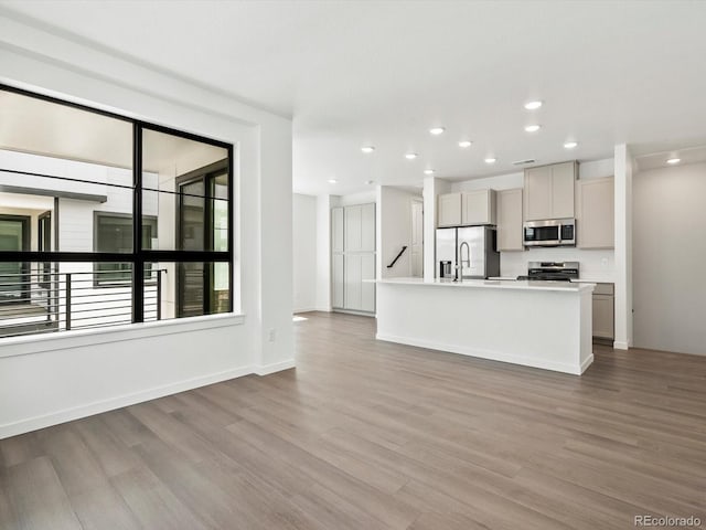 2036 S Holly St Unit 4, Denver, CO 80222 - kitchen with recessed lighting, an island with sink, light countertops, wood finished floors, and appliances with stainless steel finishes