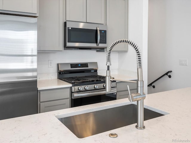 2036 S Holly St Unit 4, Denver, CO 80222 - kitchen with light stone counters, gray cabinets, stainless steel appliances, and a sink
