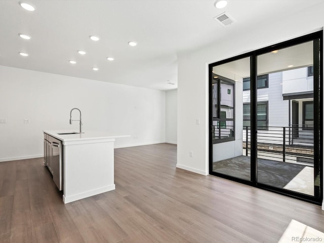 2036 S Holly St Unit 4, Denver, CO 80222 - kitchen featuring wood finished floors, a sink, an island with sink, baseboards, and visible vents