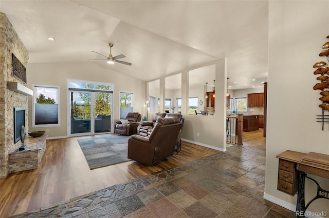 living room featuring a ceiling fan, baseboards, a fireplace, lofted ceiling, and dark wood finished floors