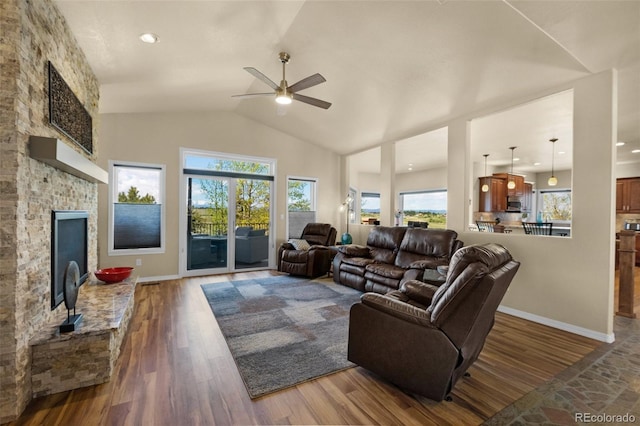 living room featuring lofted ceiling, ceiling fan, wood finished floors, a brick fireplace, and baseboards
