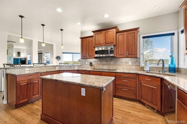 kitchen with appliances with stainless steel finishes, a sink, light wood finished floors, a peninsula, and a center island