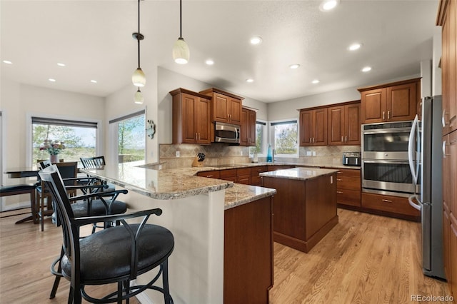 kitchen with stainless steel appliances, a peninsula, tasteful backsplash, recessed lighting, and light wood-style floors