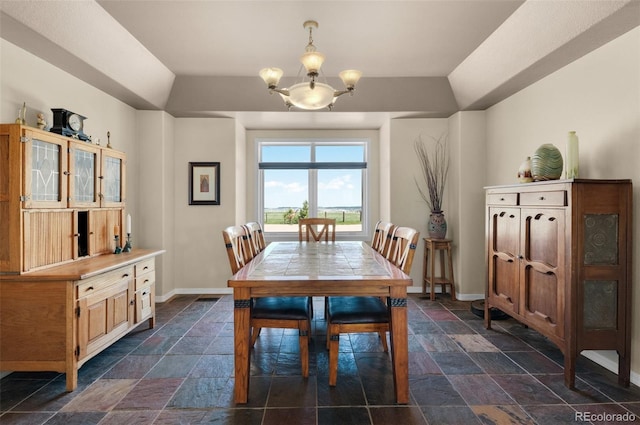 dining space with stone tile flooring, baseboards, and a chandelier