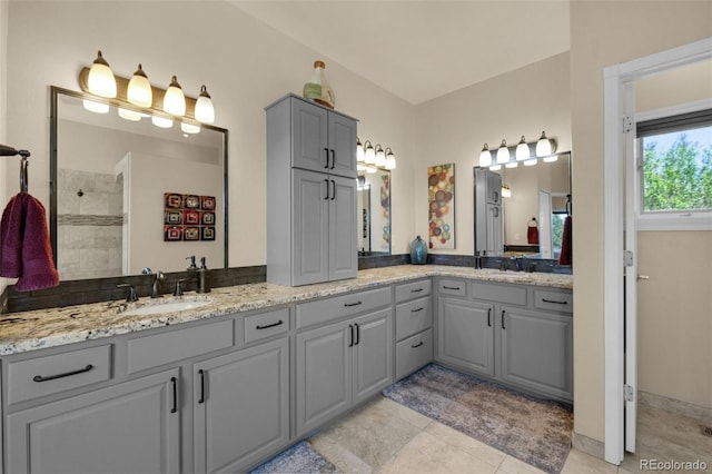 bathroom featuring double vanity, tile patterned flooring, and tiled shower