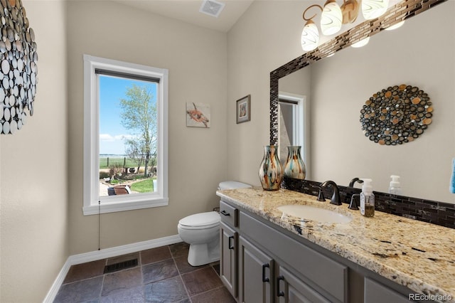 bathroom featuring plenty of natural light, toilet, baseboards, and vanity
