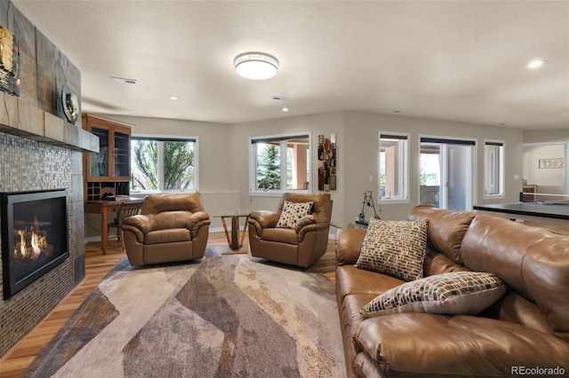 living area featuring light wood-type flooring, a tiled fireplace, and recessed lighting
