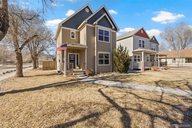 view of front of home featuring covered porch, fence, and a front yard