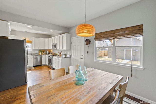 dining space with baseboards, wood finished floors, and recessed lighting