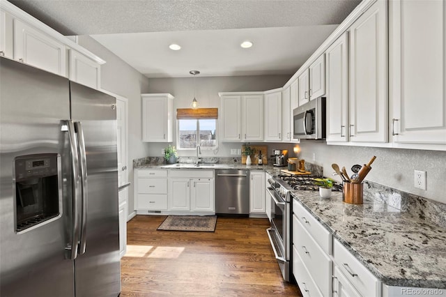 kitchen featuring stainless steel appliances, recessed lighting, dark wood-type flooring, white cabinetry, and a sink