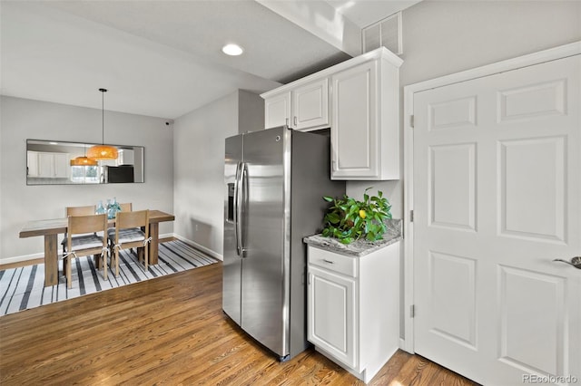 kitchen featuring visible vents, light wood-style flooring, white cabinets, light stone countertops, and stainless steel fridge